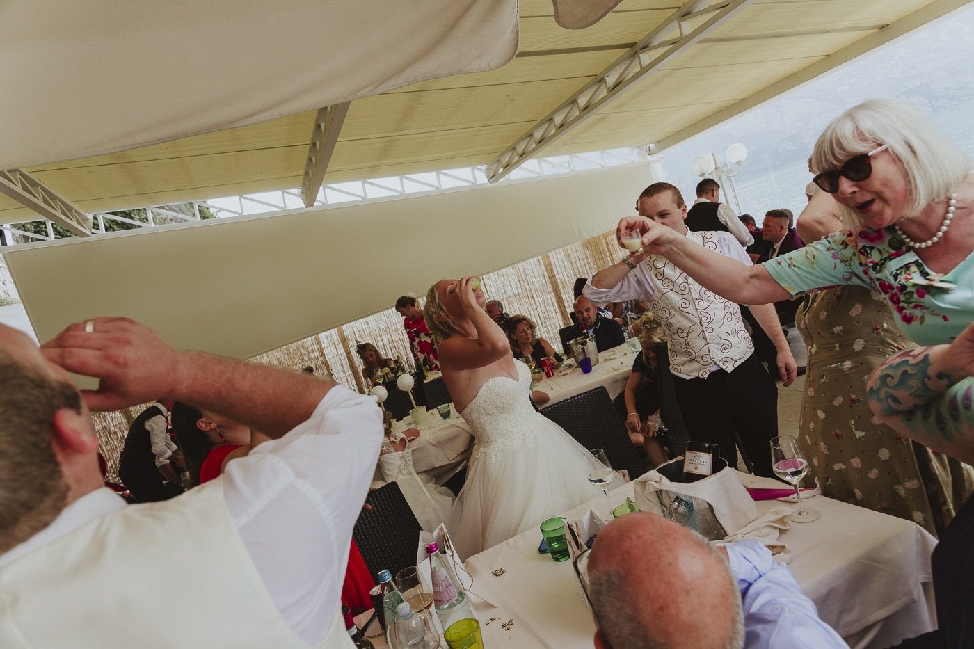 Bride, Groom and family drinking shots of alcohol amid their wedding reception by Joshua Wyborn