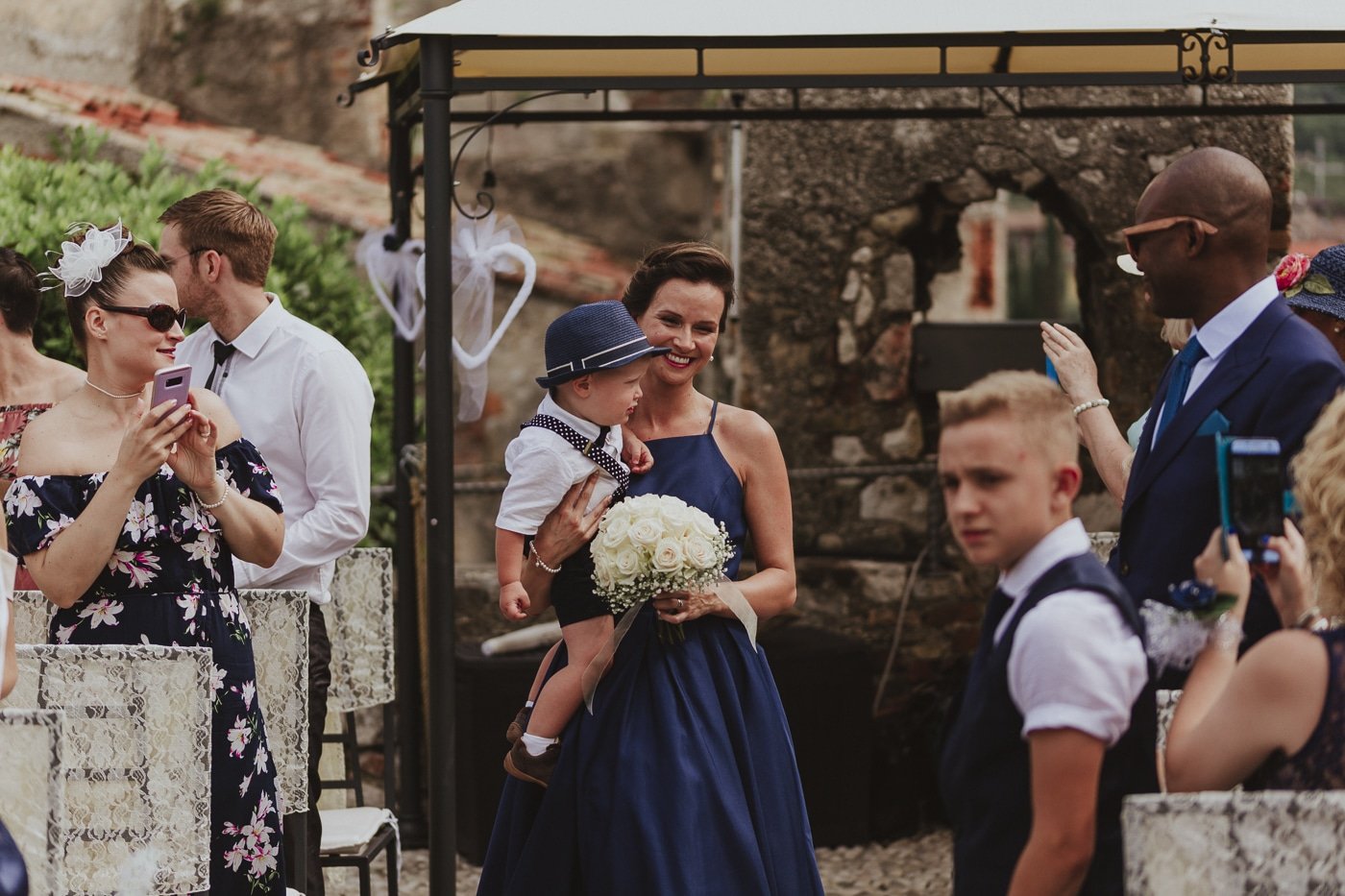 Bridesmaid and small boy in hat wait at the end of the aisle