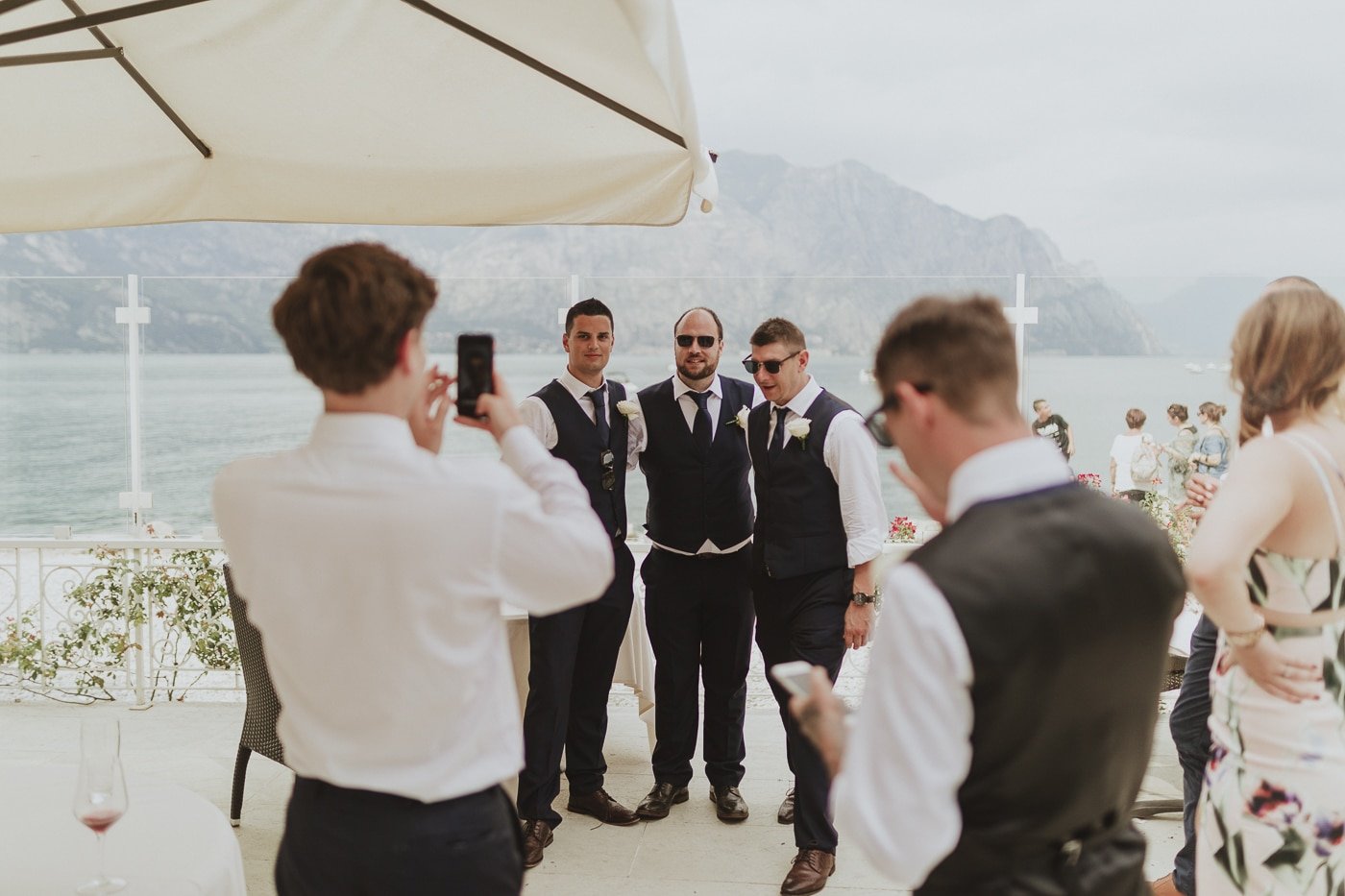 Three men in suits and waistcoats having a photo infront of the mountain and lake scenery by Joshua Wyborn