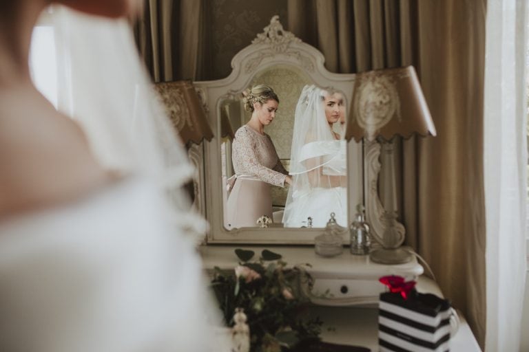 A bride at Lartington Hall looking at herself in a mirror.