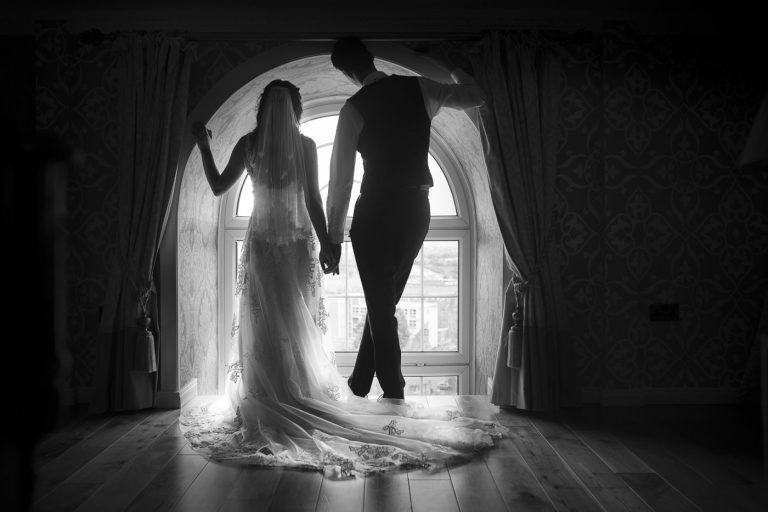 The musical love story of a bride and groom standing in front of a window.
