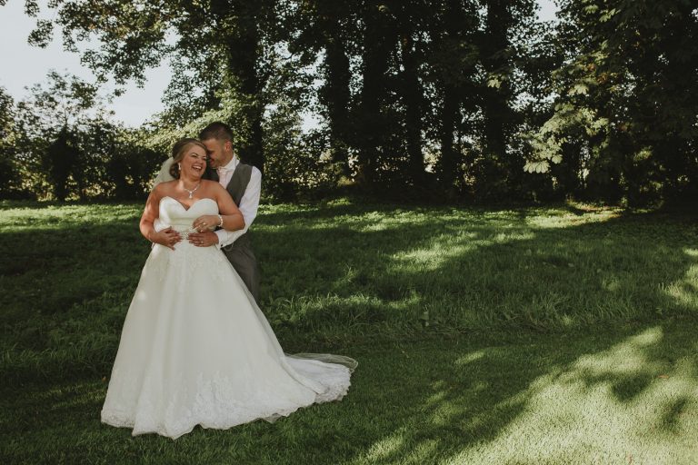 A bride and groom embracing in the beautiful Greenhill Hotel field.