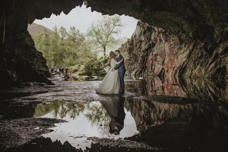 A bride and groom sharing a passionate Kiss of Life in front of a majestic cave