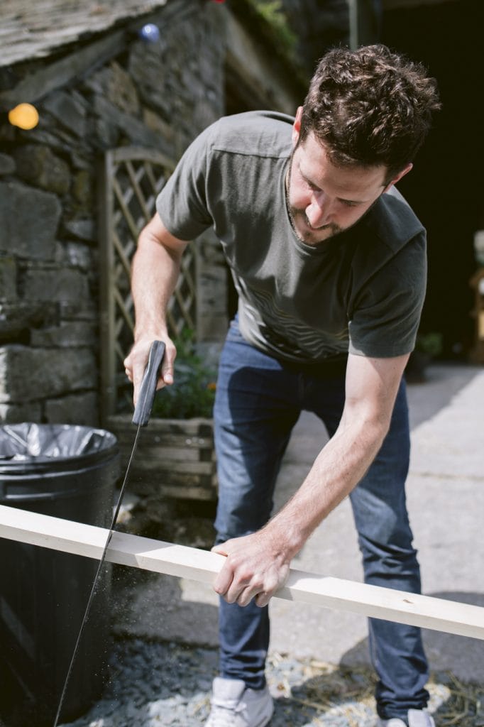Groom Cutting Wood at Yew Tree Farm Wedding