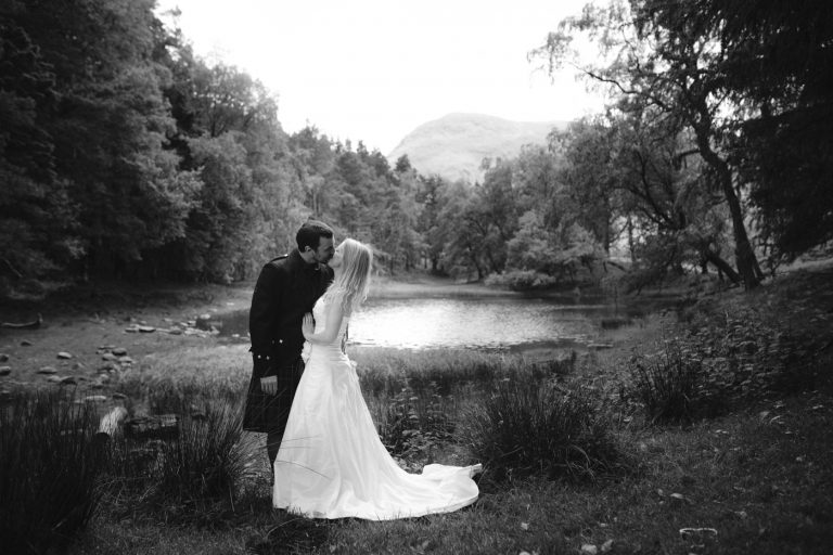 Bride and Groom Wedding Dress Kissing Together near Lakeside Portrait Session