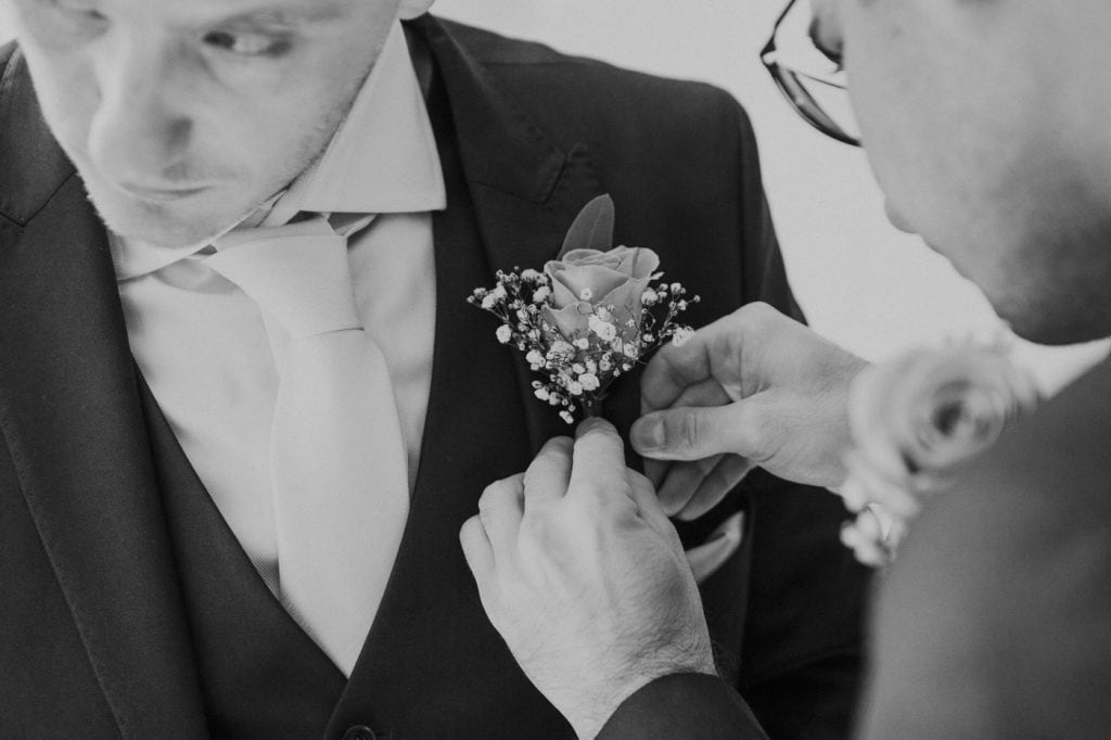 Additional Photographer Photograph at Groom Prep of button hole being put on
