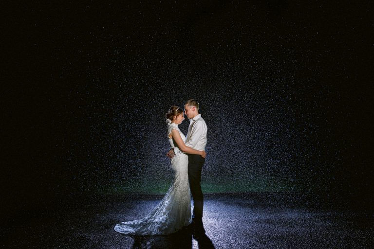 Dalston Church Wedding - A bride and groom standing in front of a waterfall at night.