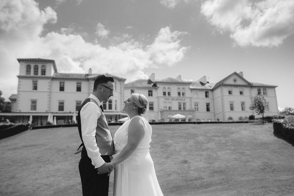 A Belsfield wedding with the bride and groom standing in front of a large mansion.