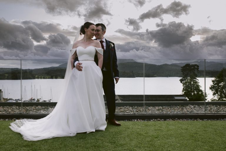 A bride and groom posing in front of Low Wood Bay
