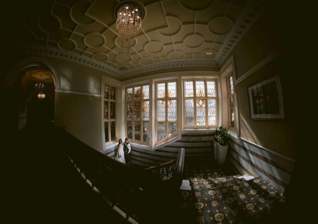 A bride standing on a staircase in the Crown and Mitre Hotel Wedding, a dark room.