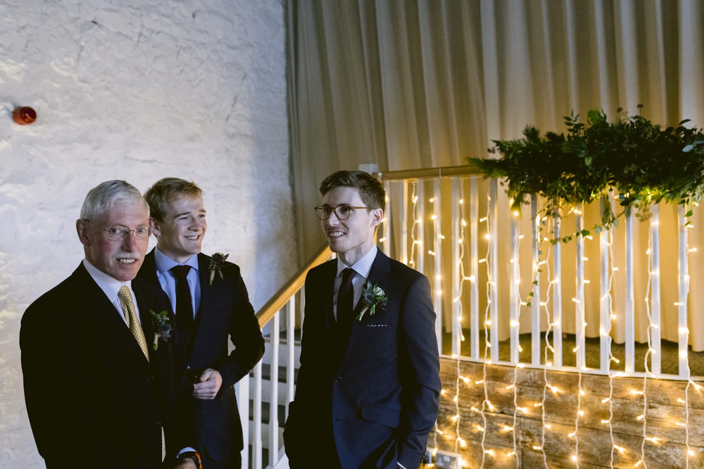 Two men standing next to each other in front of a Askham Hall staircase.