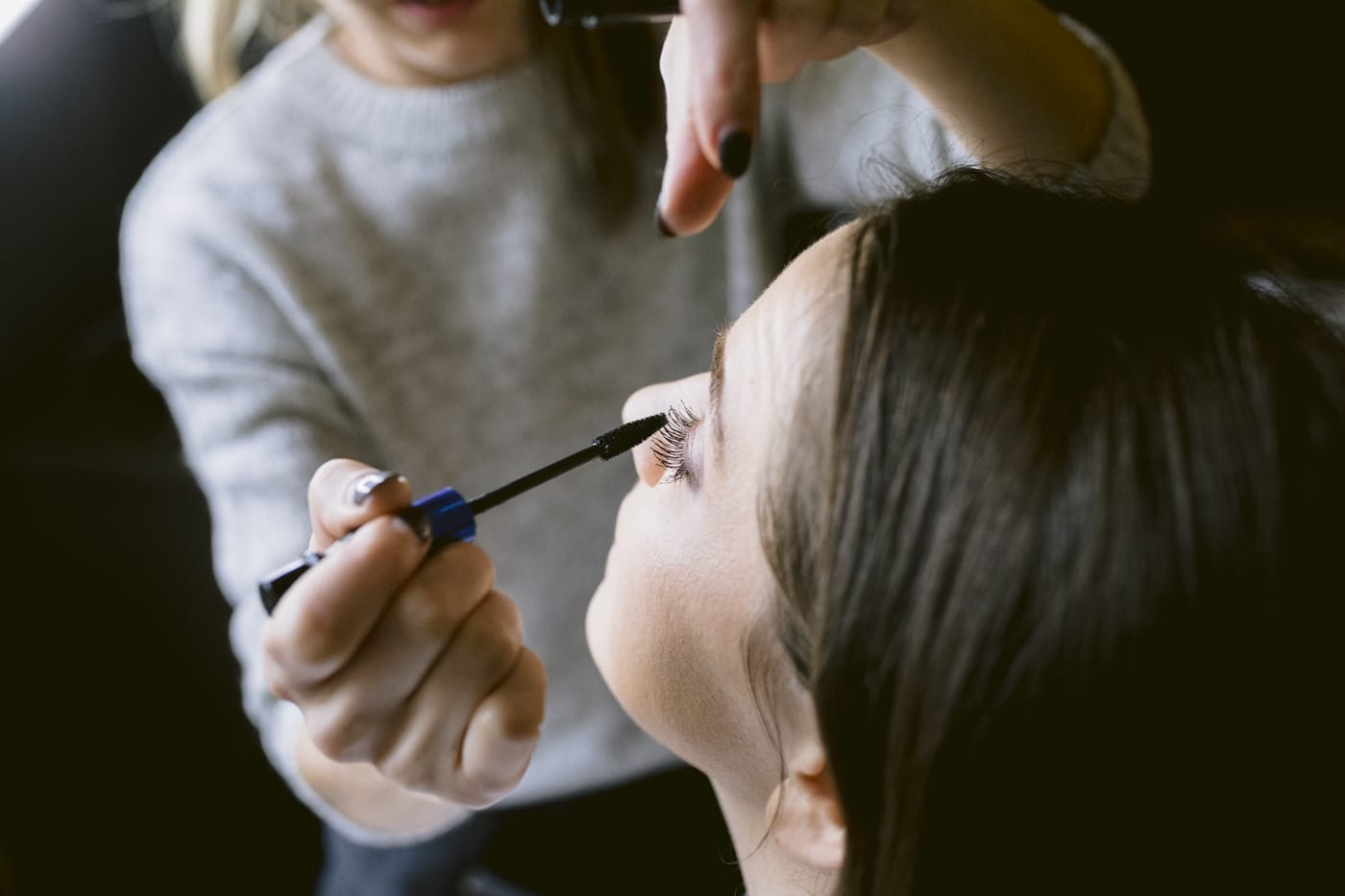 A woman is getting her makeup done by a makeup artist at Askham Hall.