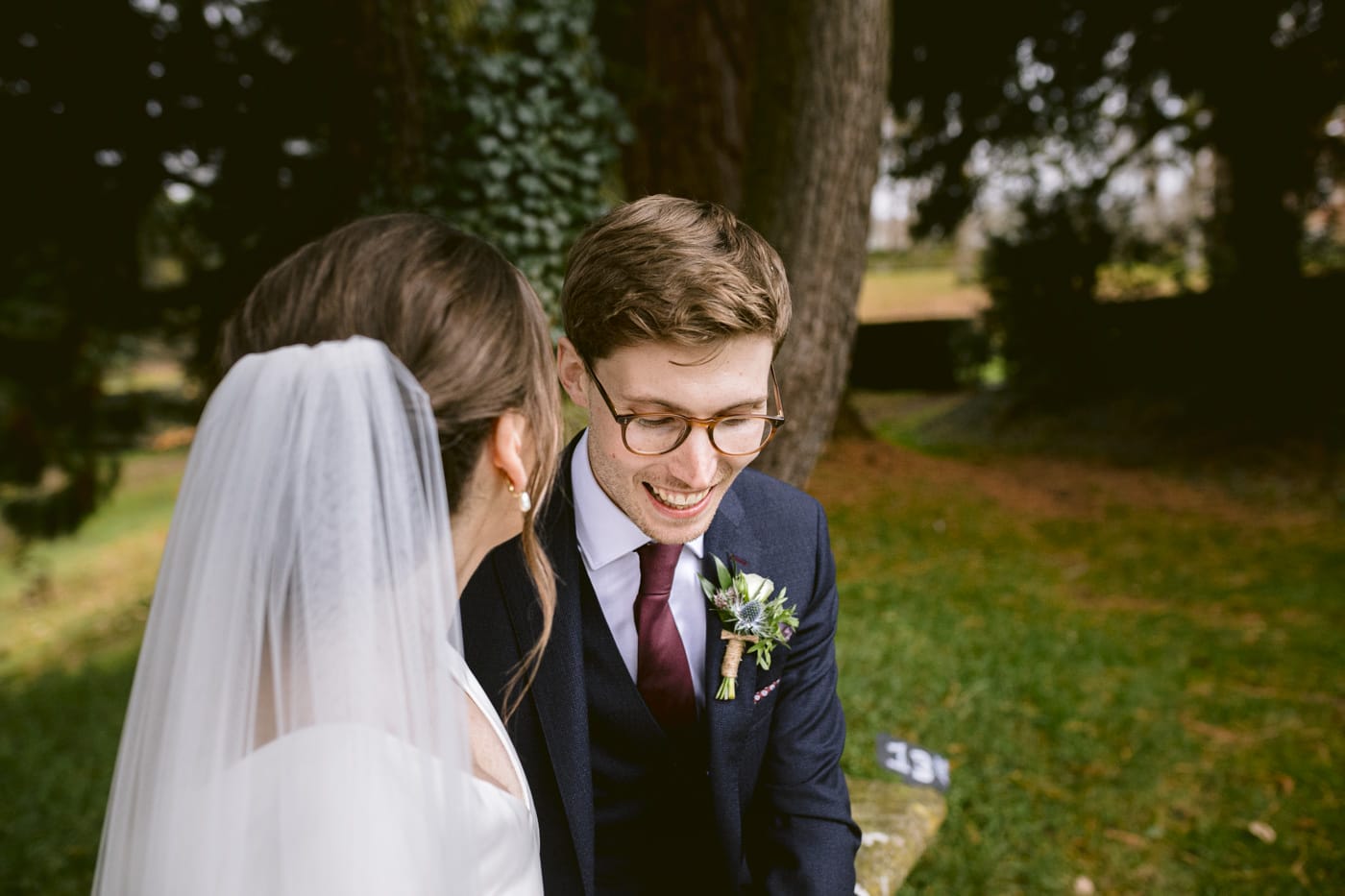 A bride and groom sitting on a bench at Askham Hall, gazing lovingly at each other inside Bank Barn.