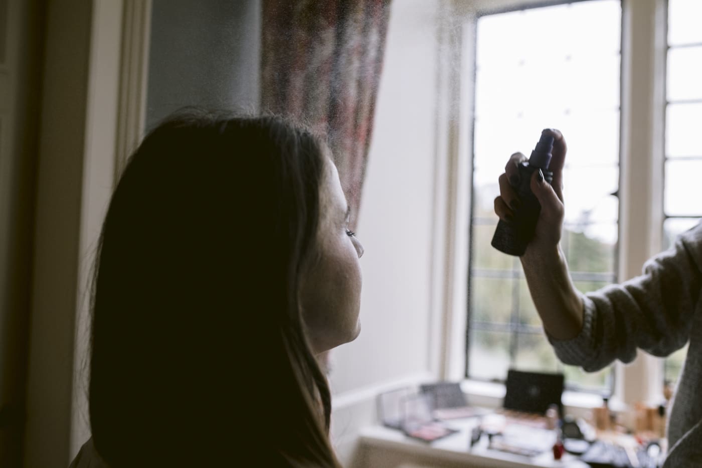 A woman is getting her hair done in front of a window at Askham Hall.