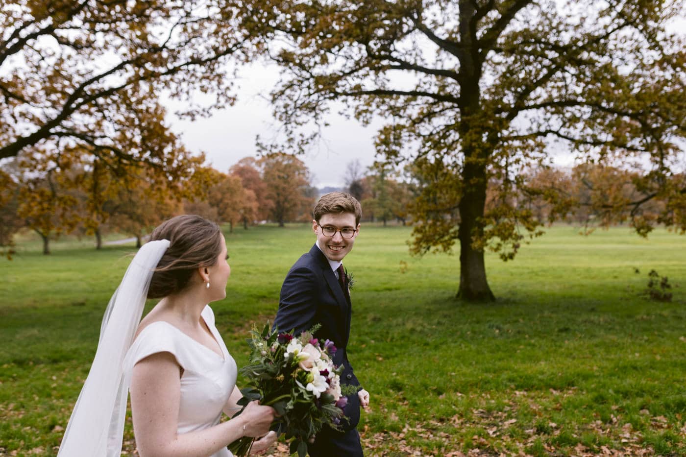 A bride and groom walking through Askham Hall park.