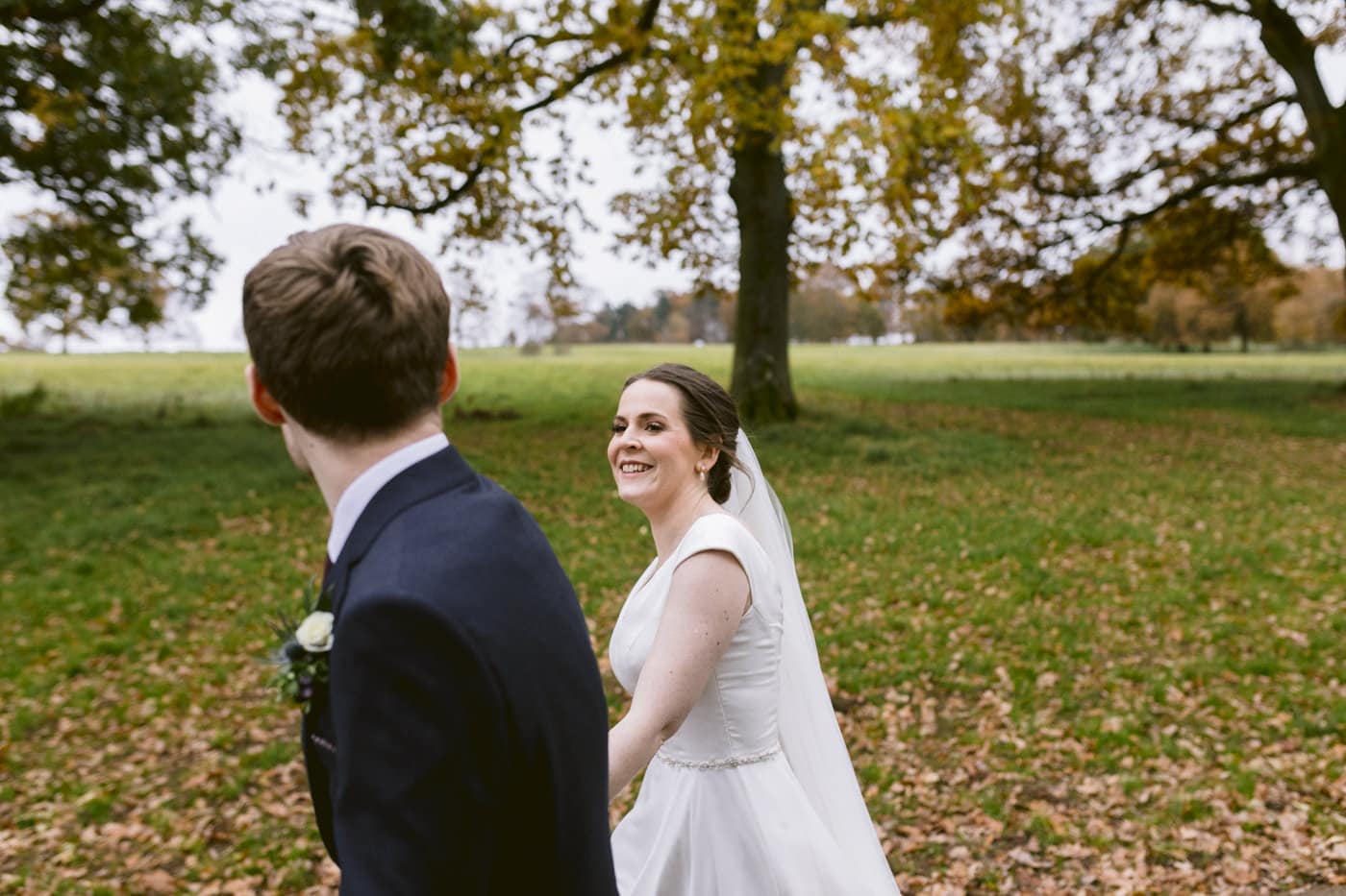 A bride and groom walking through Askham Hall garden in autumn.