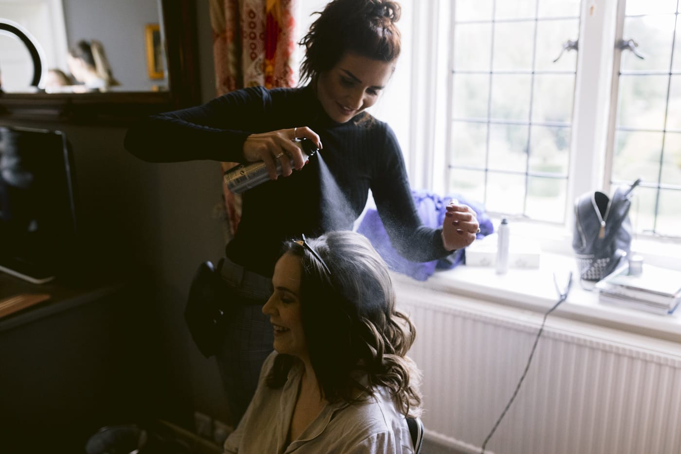 A woman getting her hair done in front of a window at Askham Hall.
