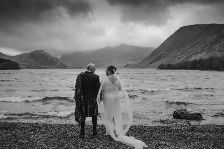 A post wedding portrait session of a bride and groom standing on the shore of a lake.