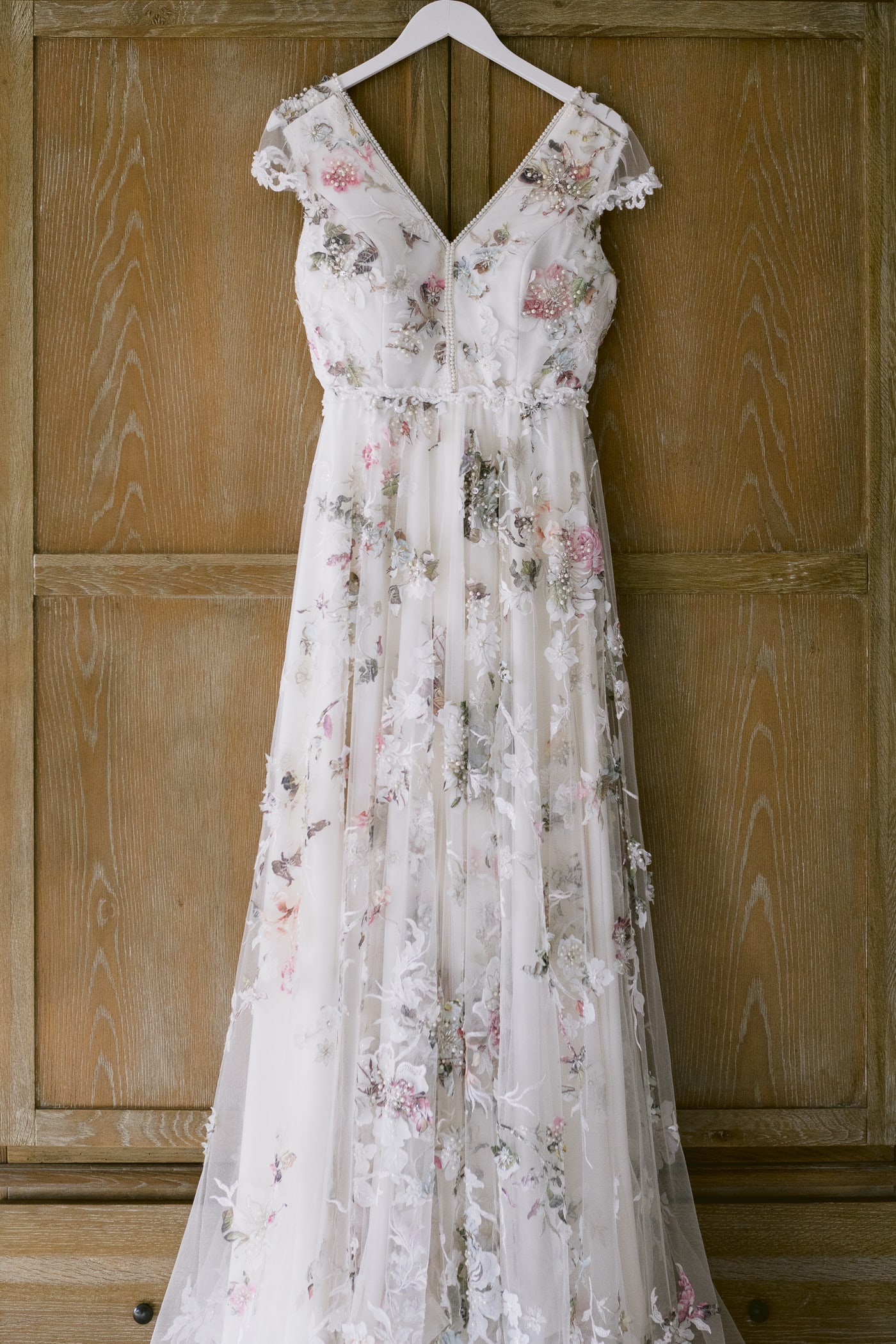 A Hexham House wedding dress hanging on a wooden door.