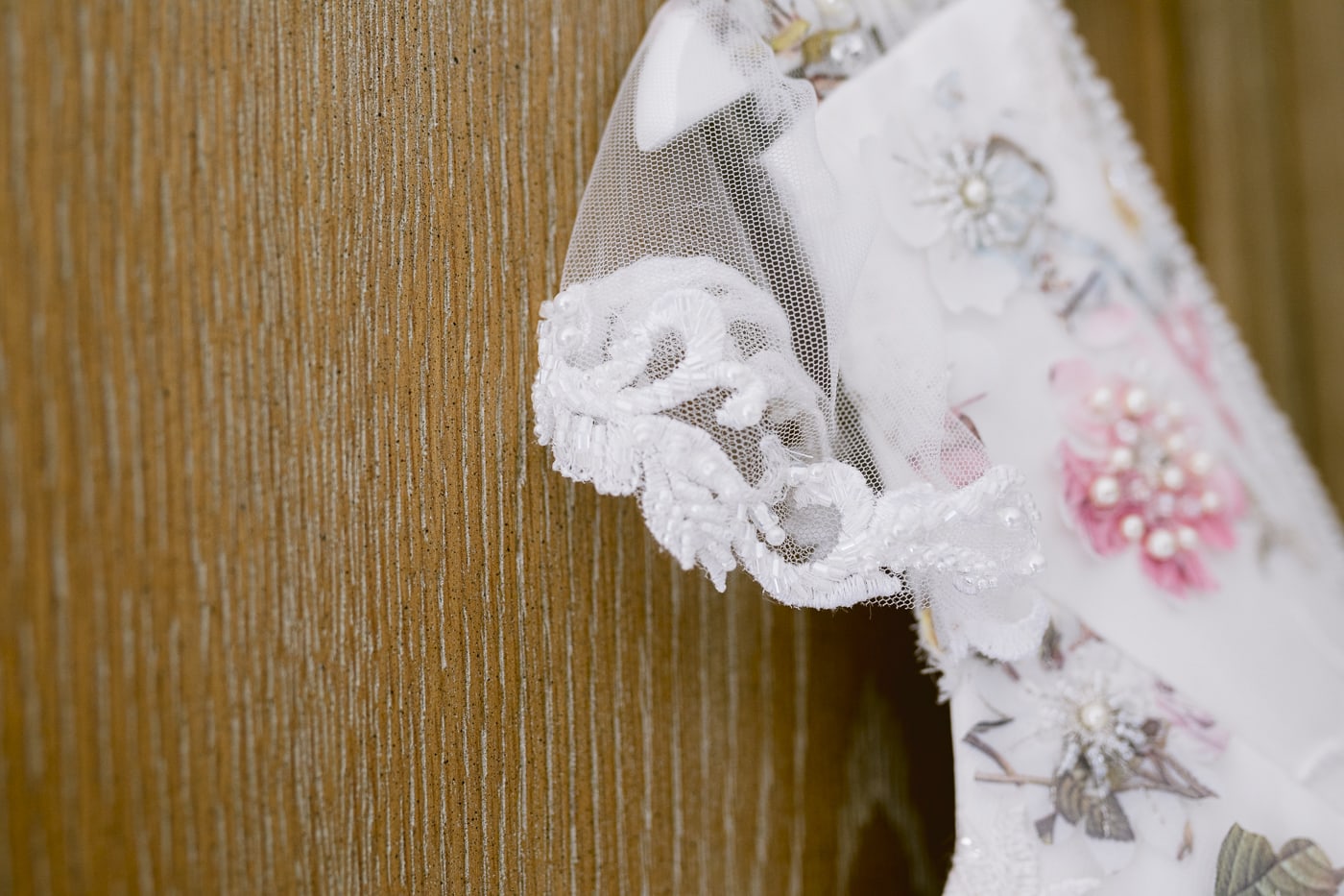 A Hexham House wedding dress gracefully hangs on a wooden door.