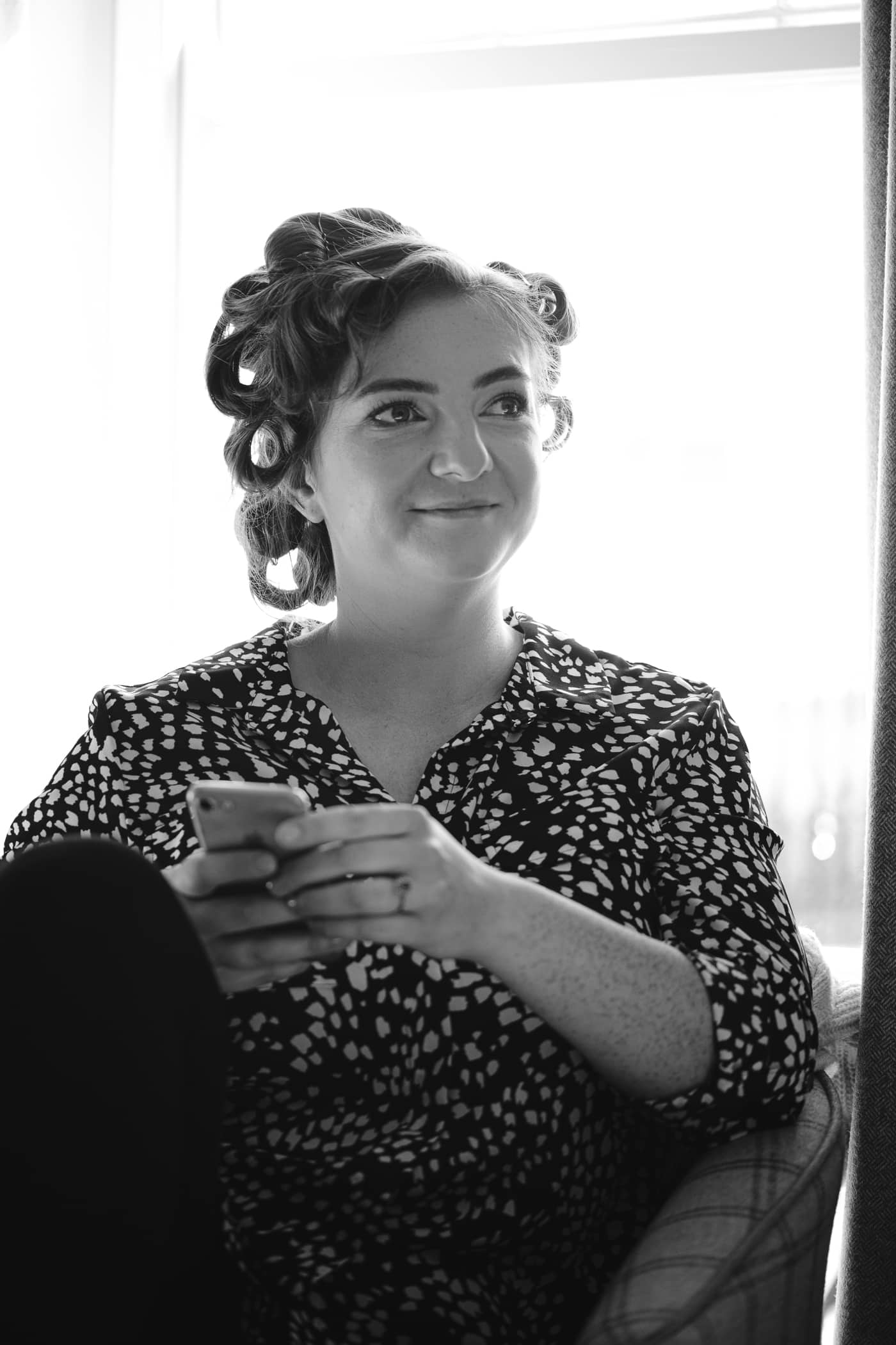 A woman at Hexham House Wedding sitting in a chair looking at her phone.