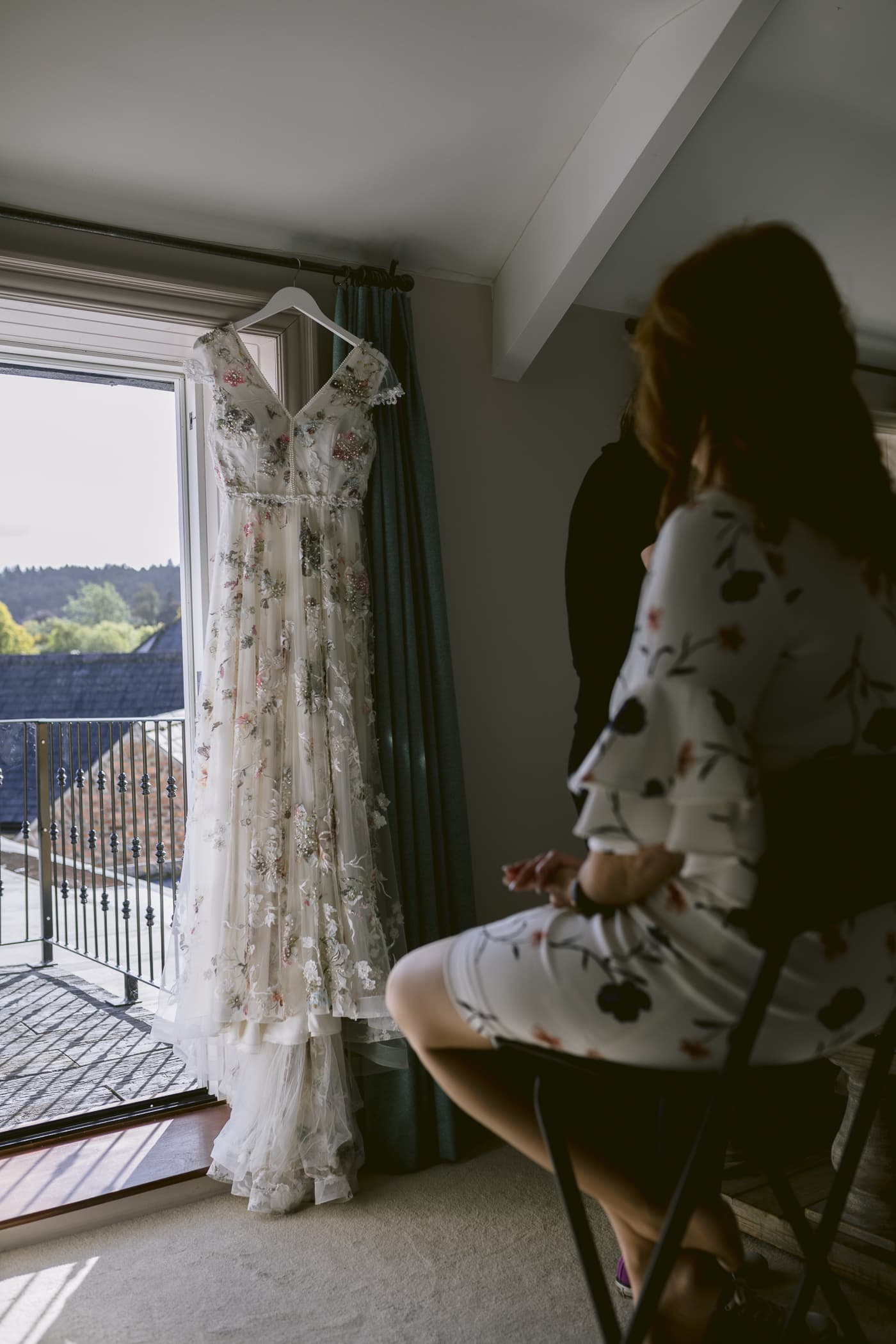 A woman is sitting in a chair at Hexham House, looking at her wedding dress.
