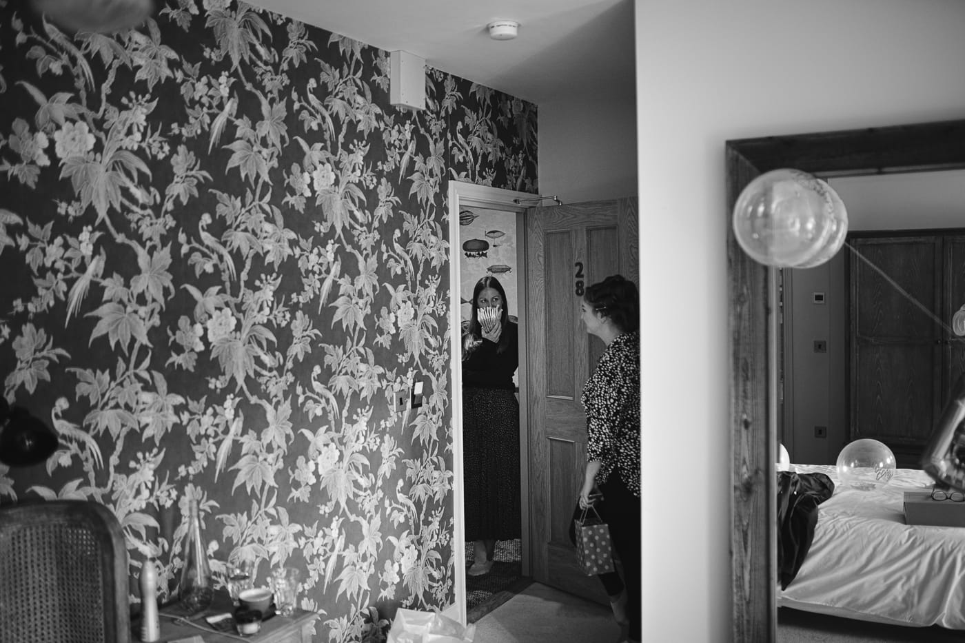 A black and white photo of a woman standing in front of Hexham House, a wedding venue, door.