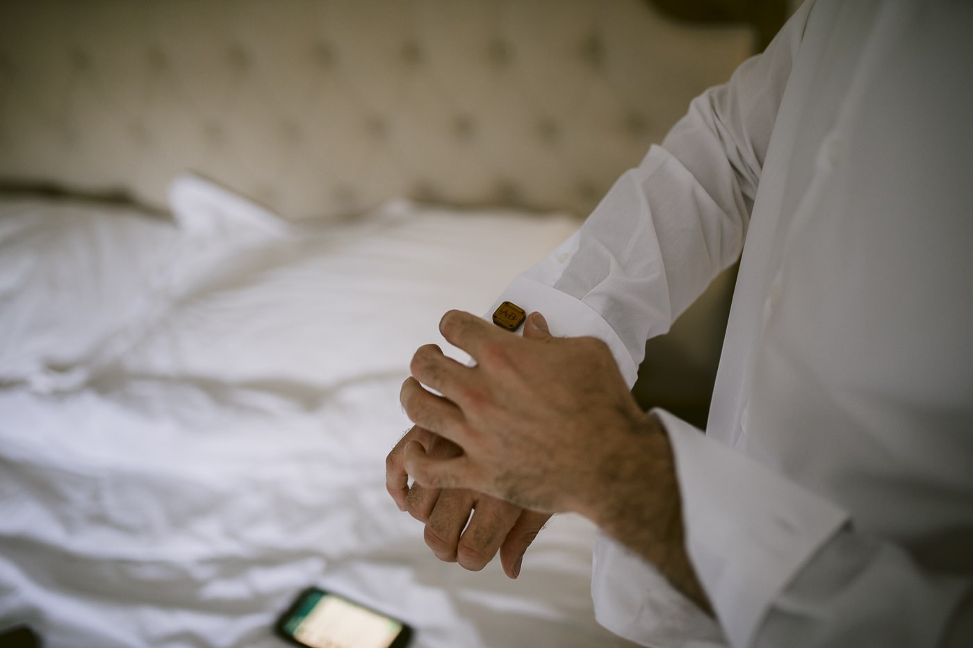 A man is adjusting his cufflinks in a Hexham House Wedding.