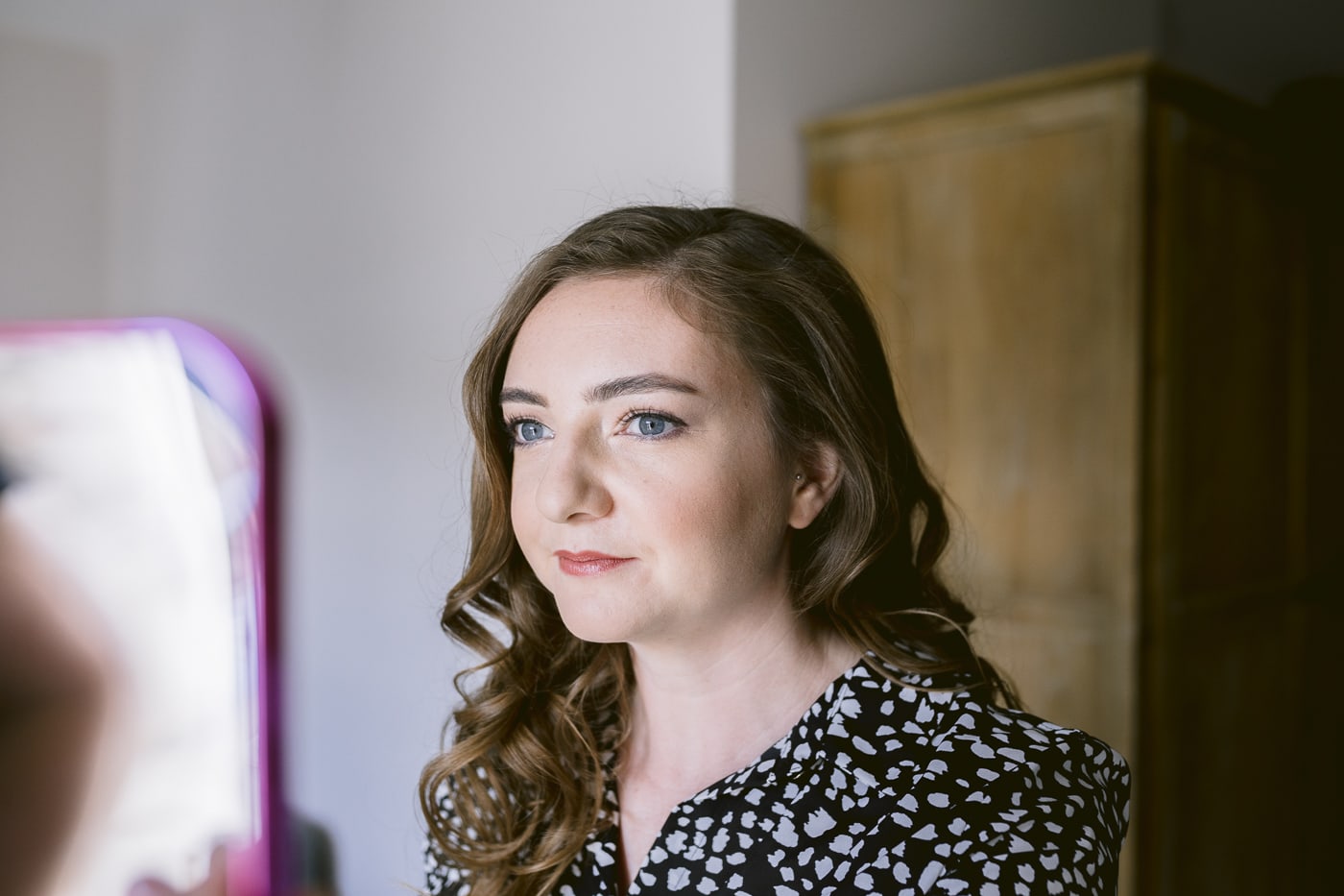 A bride is getting ready in front of a mirror at Hexham House before her wedding.