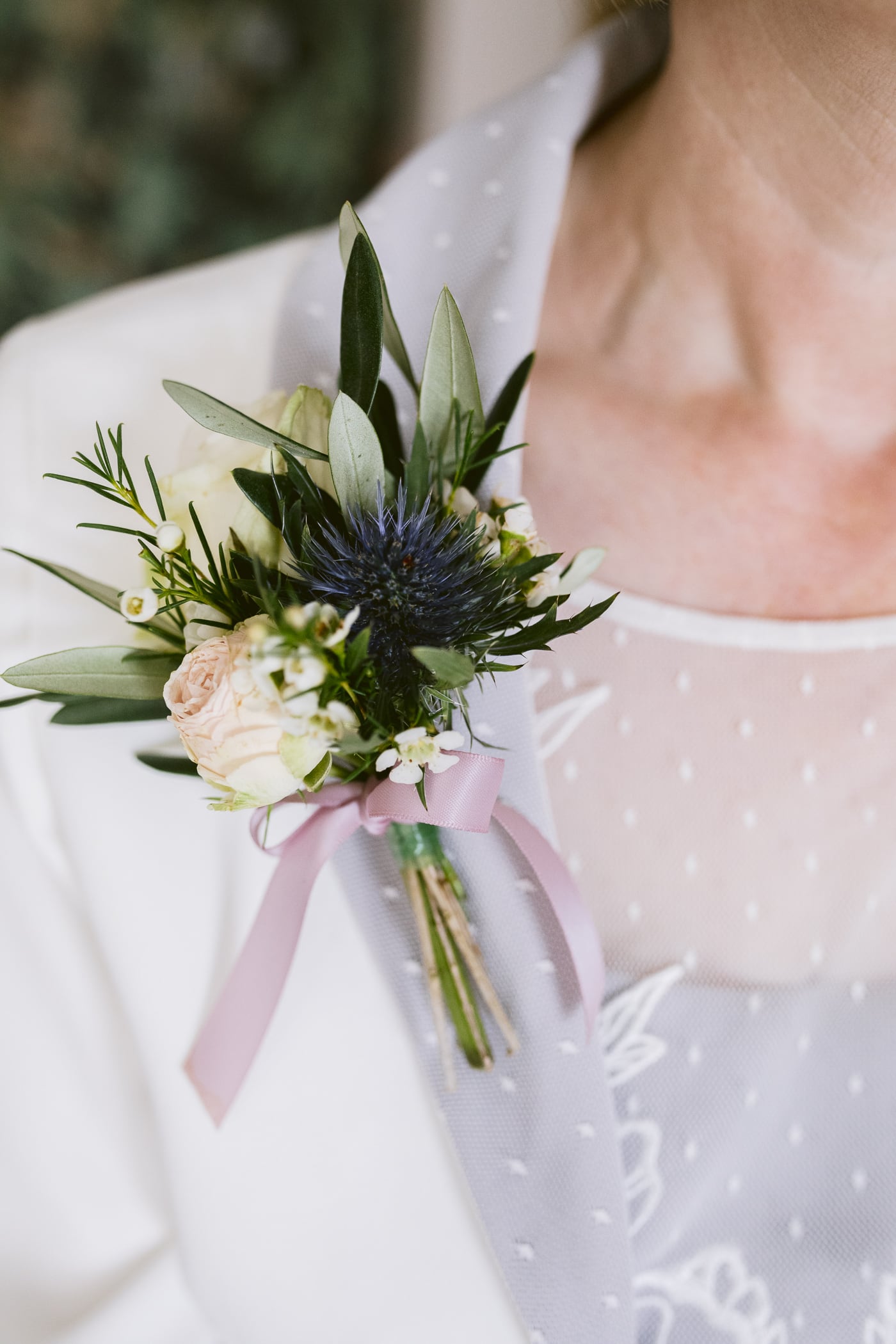 A woman is wearing a flower boutonniere at the Hexham House Wedding.