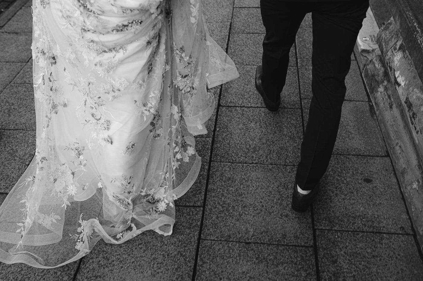Hexham House Wedding - a black and white photo capturing a bride and groom walking down the street.