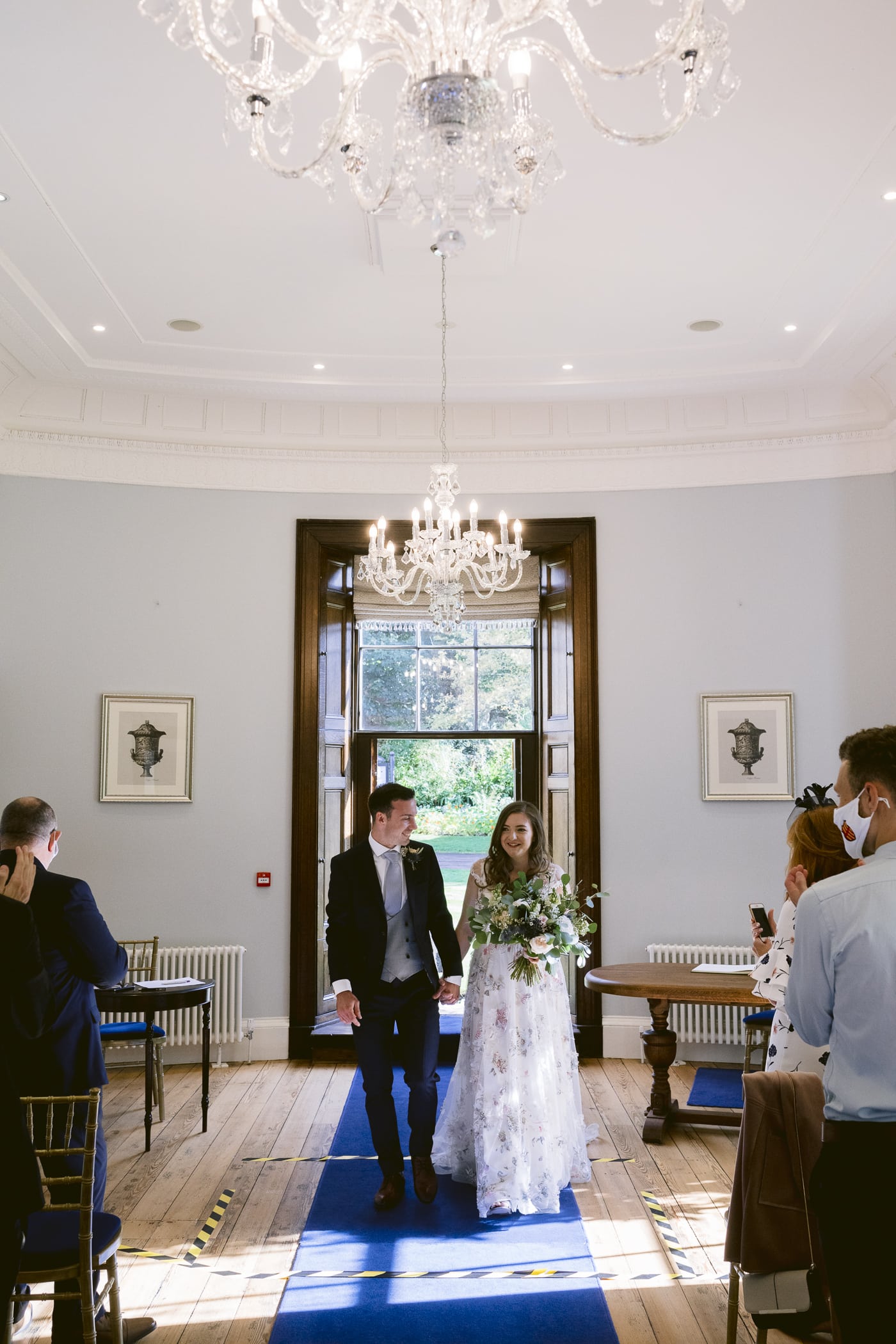 A breathtaking Hexham House wedding unfolds as a radiant bride and groom gracefully walk down the aisle, embracing the joyous atmosphere of their special day.