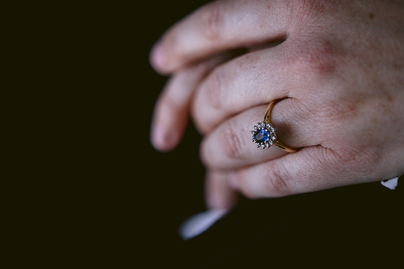 A woman's hand showcasing a stunning blue sapphire ring from Hexham House Wedding.