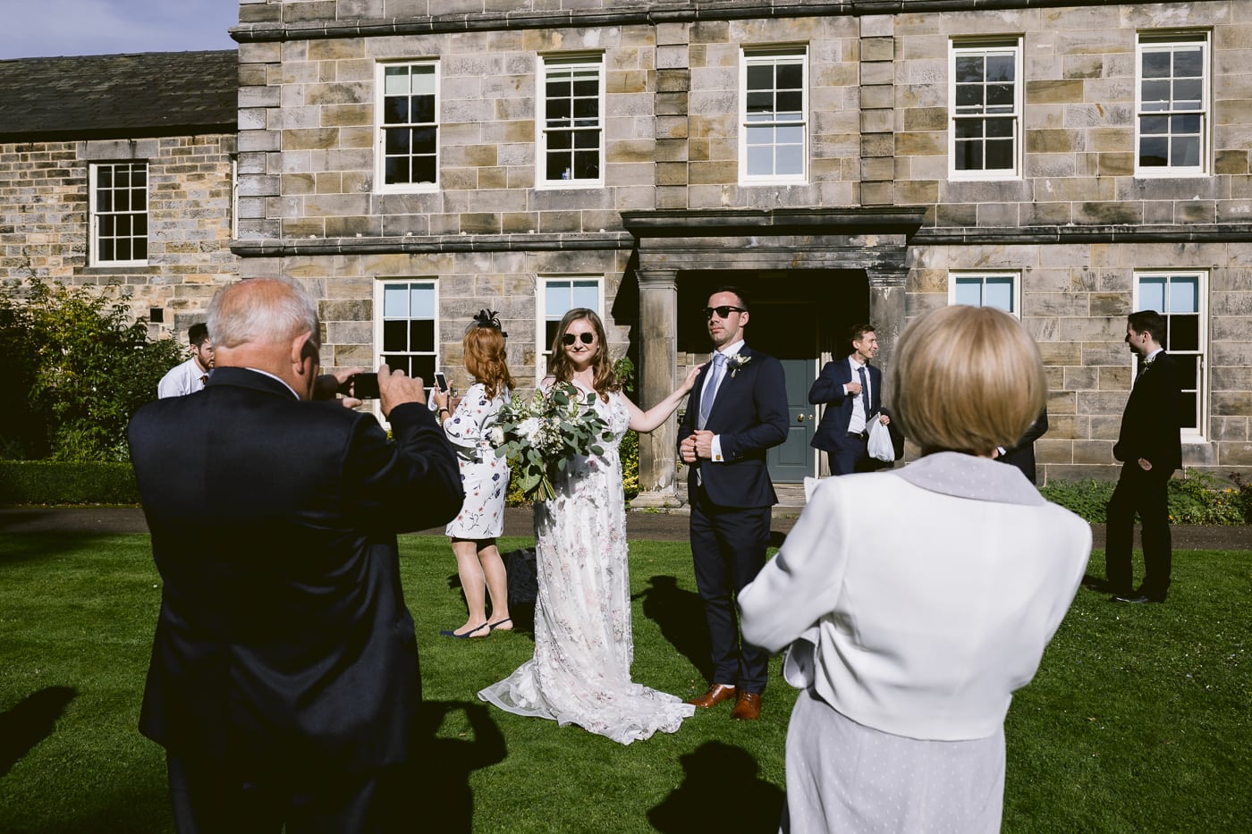 A Hexham House bride and groom taking pictures in front of a large building.