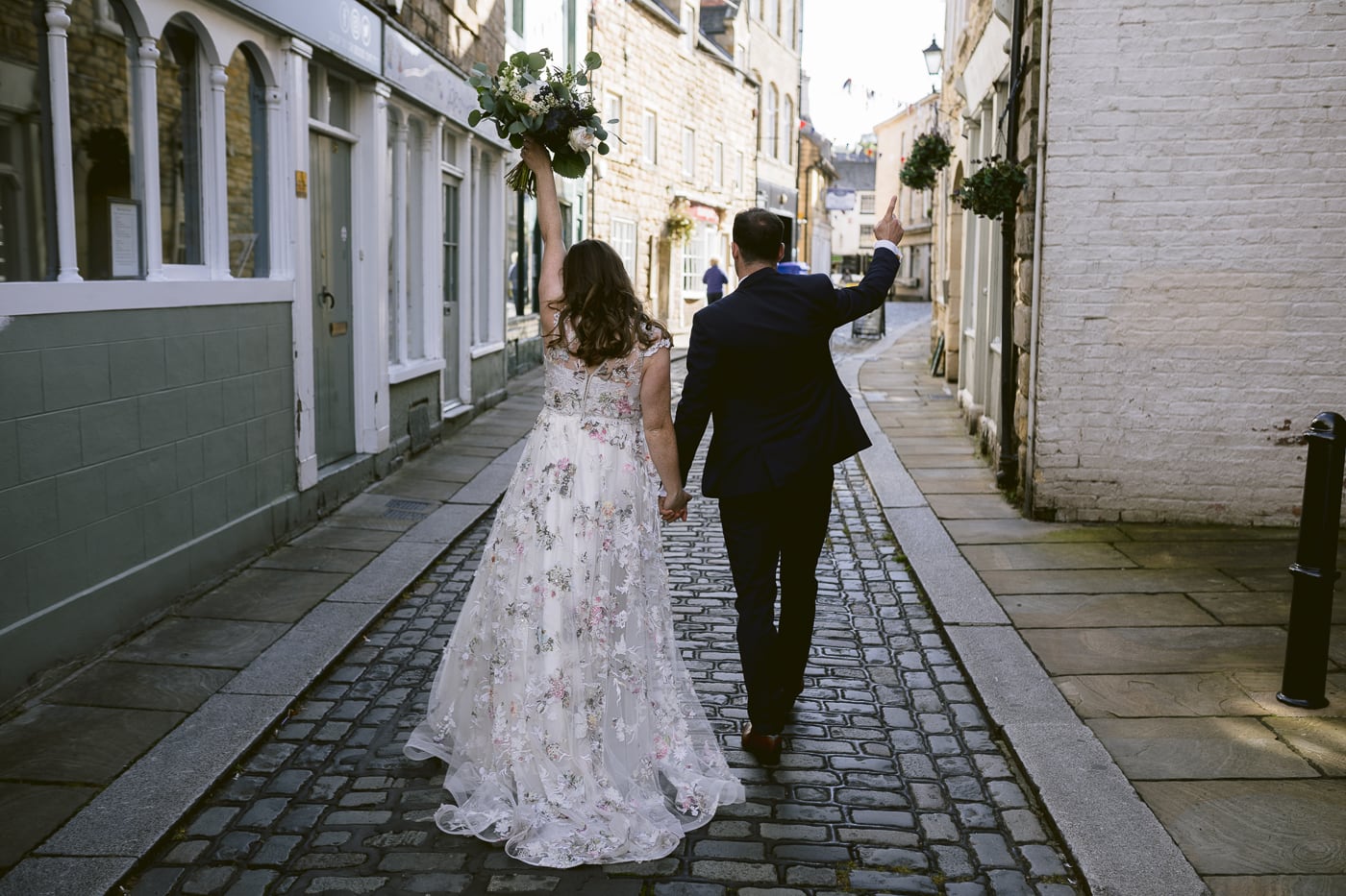 A Hexham House Wedding bride and groom walking down a cobblestone street.