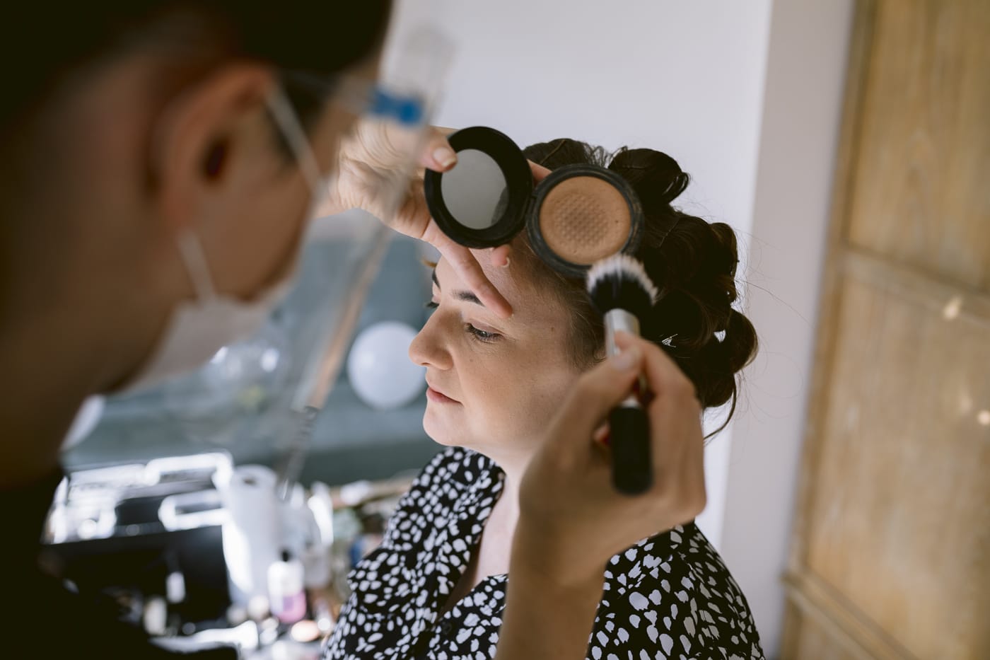 A bride is getting her makeup done by a makeup artist for her Hexham House wedding.