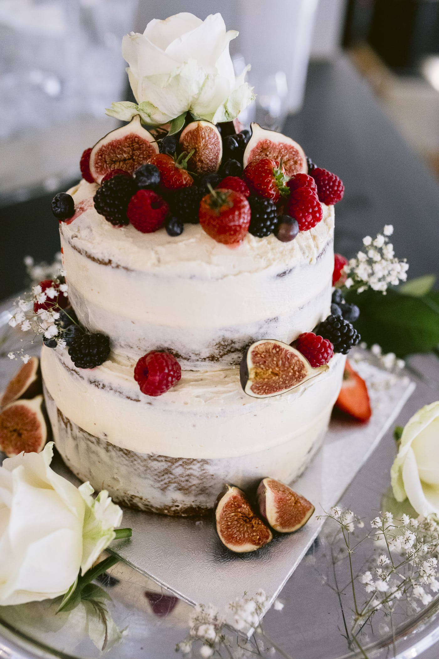 A Hexham House wedding cake adorned with luscious berries and delicate flowers on top.
