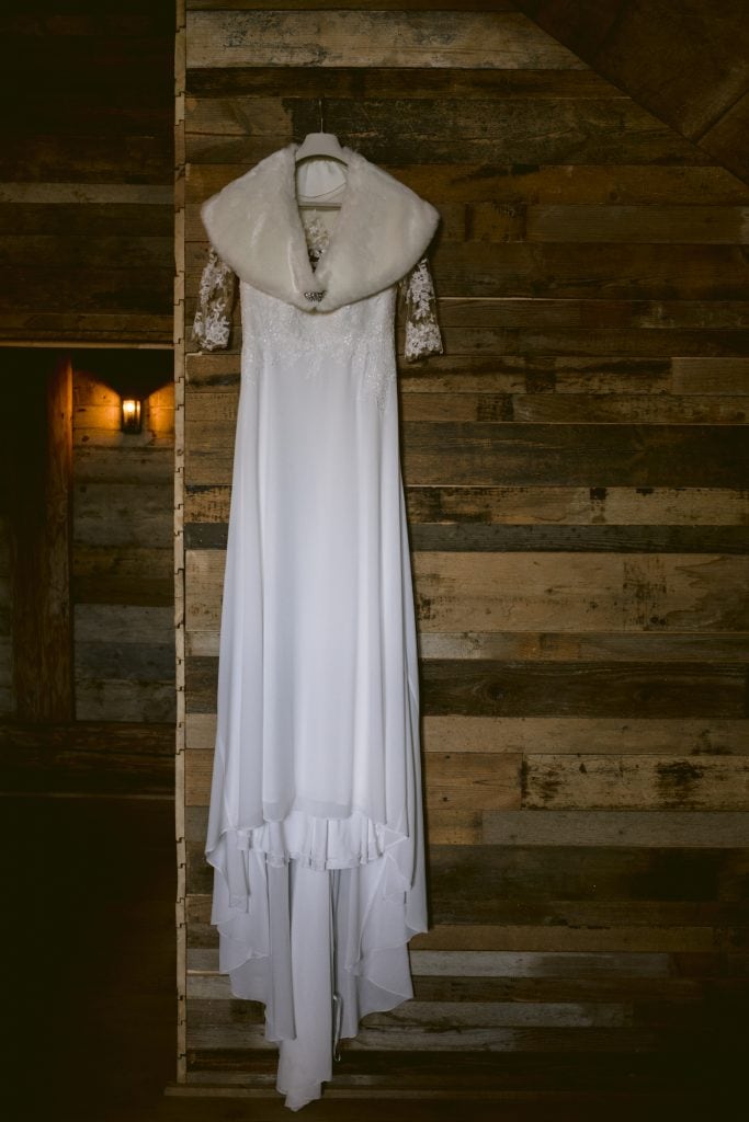 A beautiful white wedding dress adorns the wooden wall of Hidden River Barn.