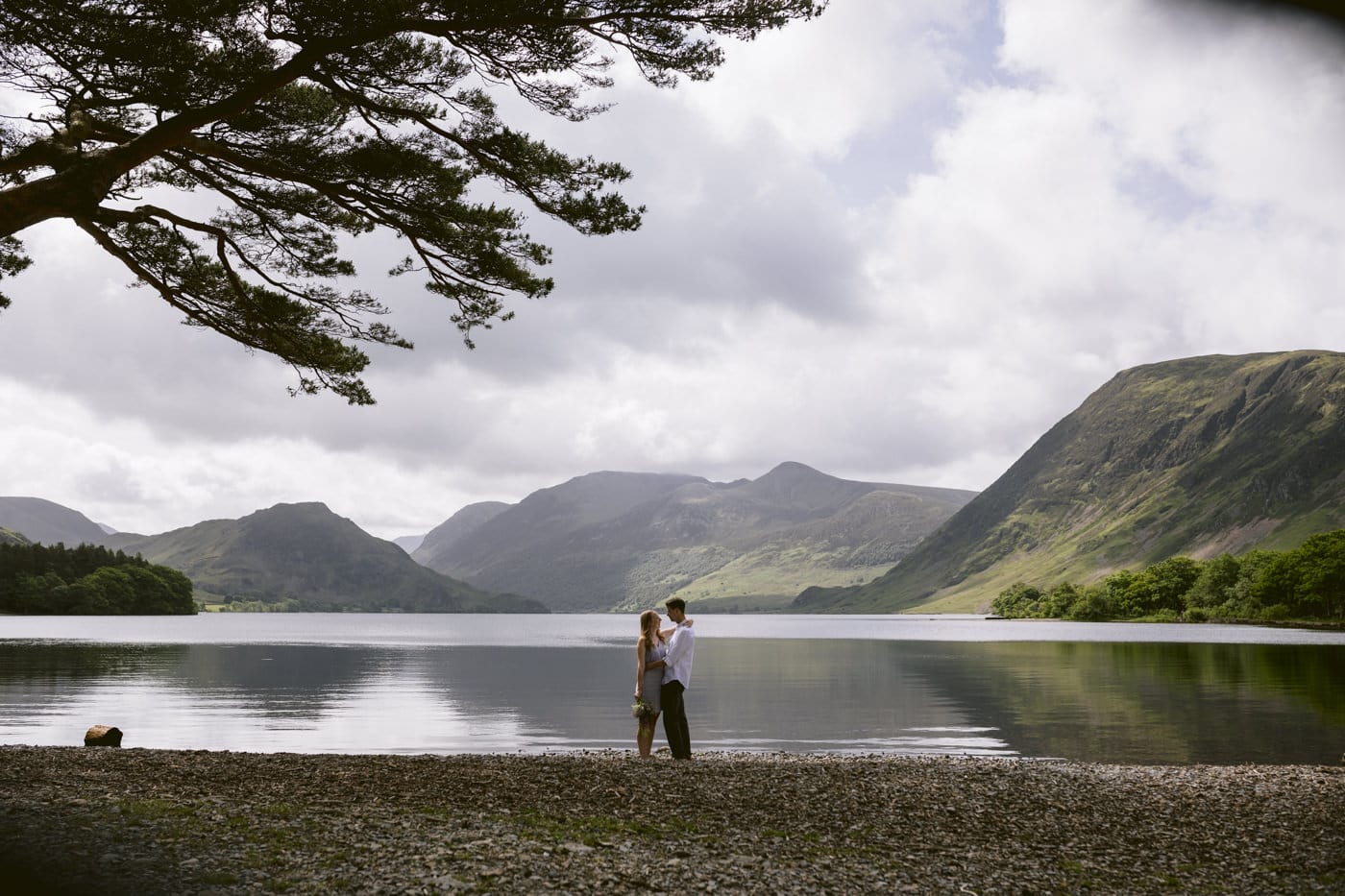 A couple standing on the shore of Lake District.