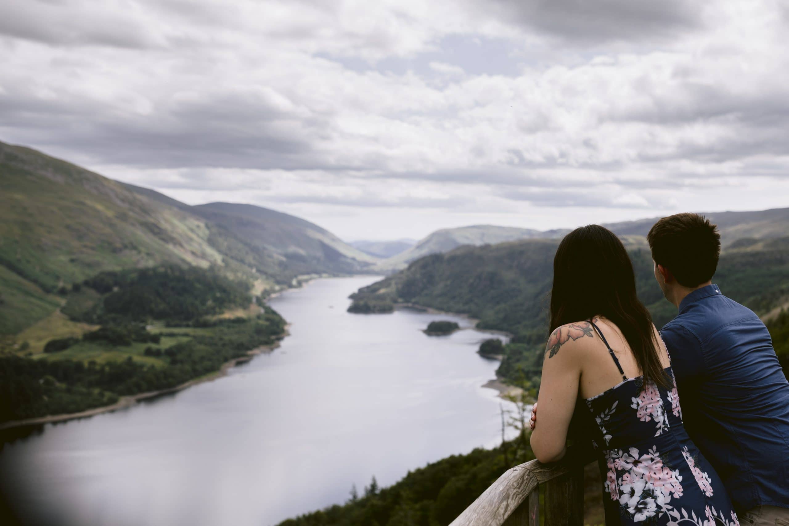 A couple enjoying a serene view of a lake in Scotland during their portrait session.