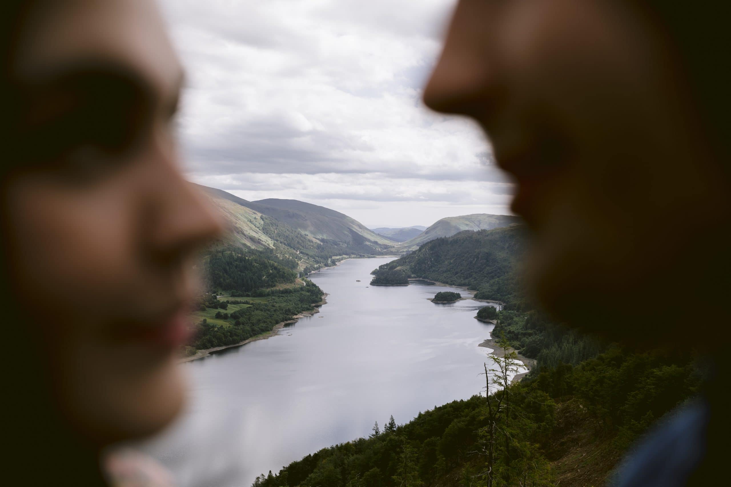 A couple enjoying a serene lake view with mountains in the background during their portrait session.