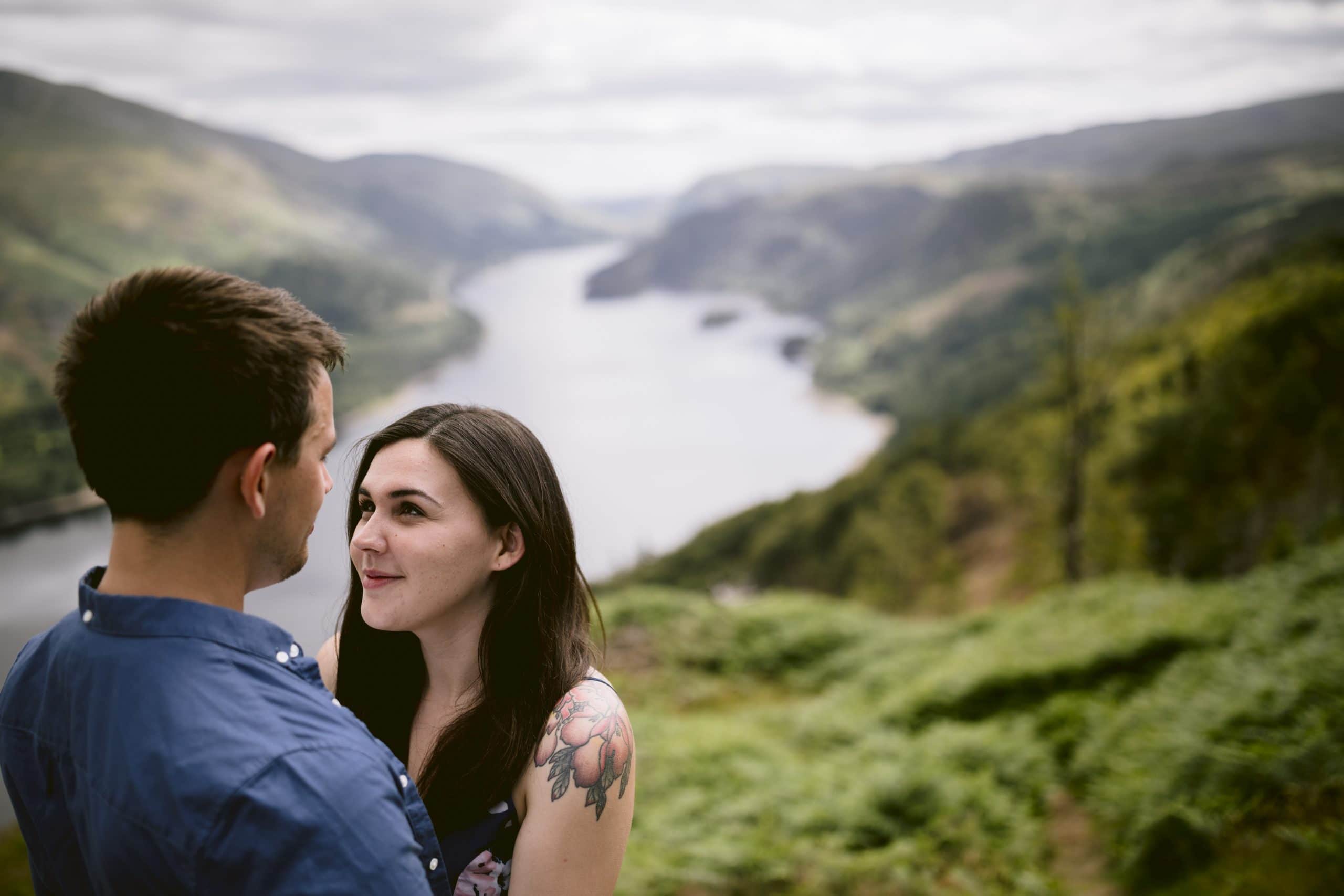 A couple having a romantic portrait session while standing on a hill overlooking a lake.