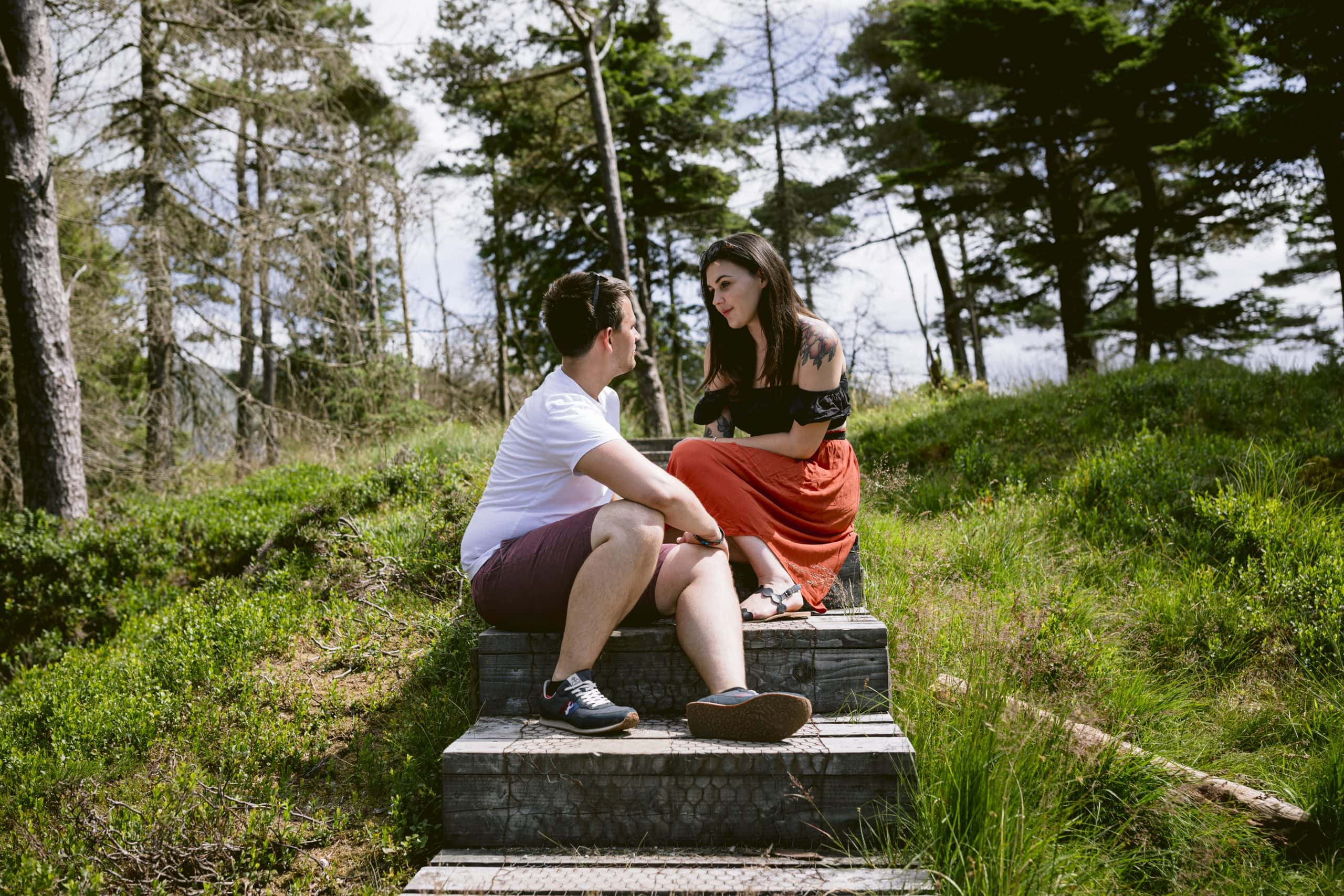 A couple sitting on steps with a serene lake in the background.