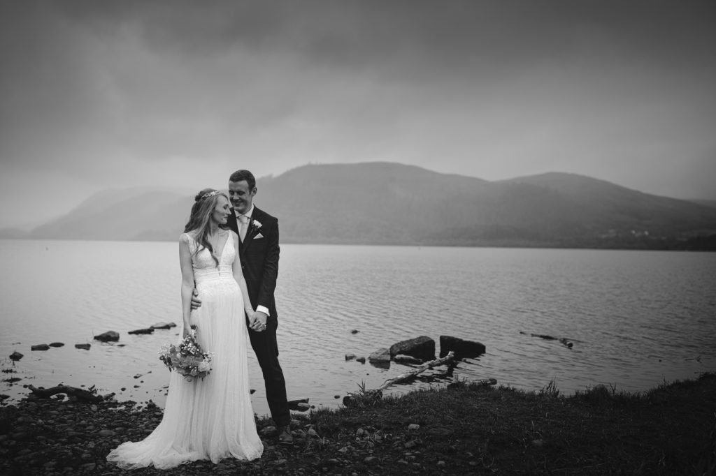 A wedding couple standing in front of a lake at Armathwaite Hall.