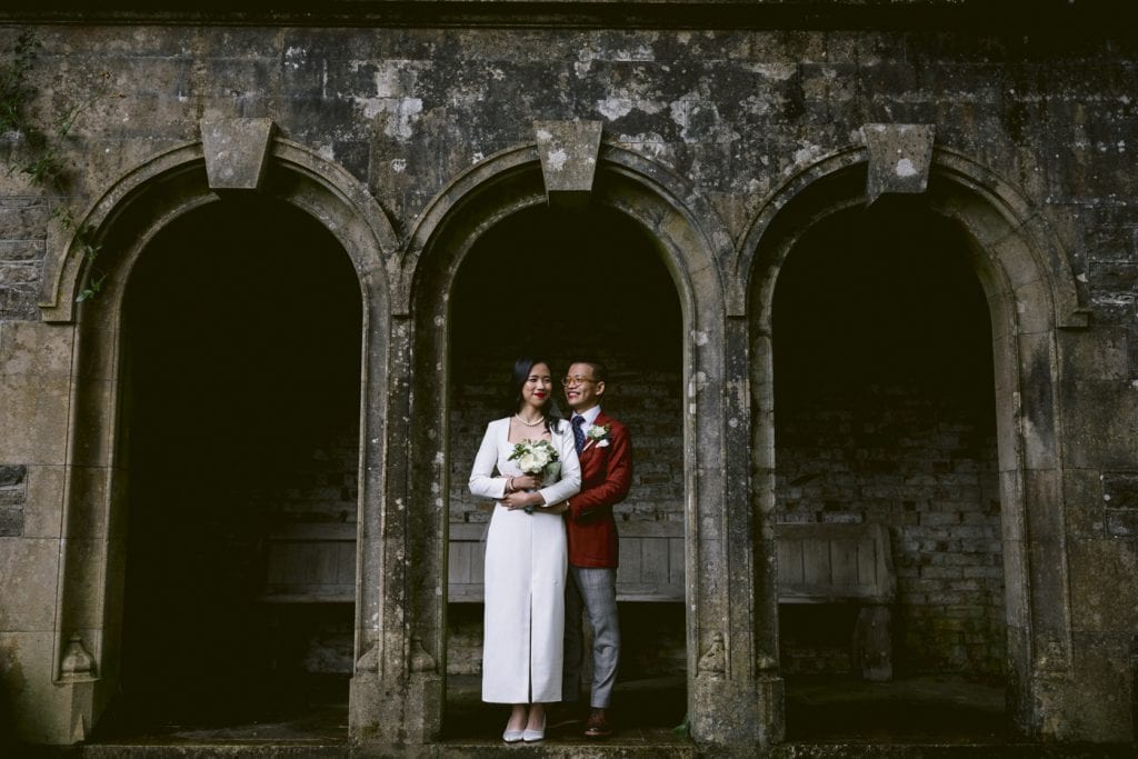 A Marvel-themed wedding with a bride and groom posing in front of arches in an old building.