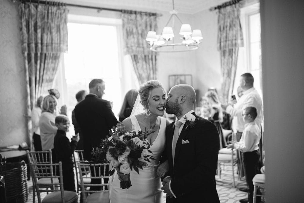 A bride and groom kissing at Storrs Hall, in a black and white photo.