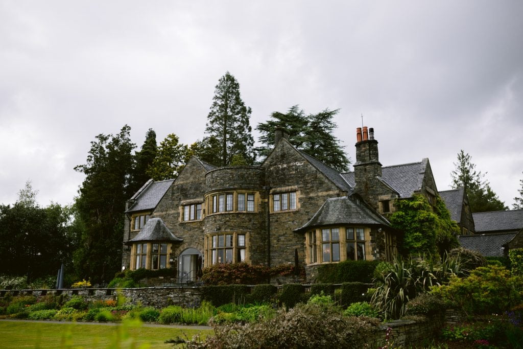 A Double Elopement at Cragwood Country House Hotel, a large stone house in the middle of a lush green field.