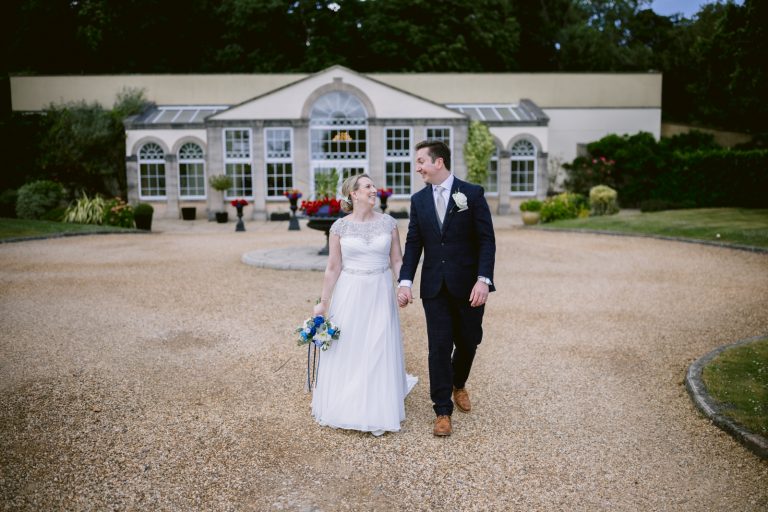 Bride and groom walking in front of the pavillion at Whittlebury weddings northampton