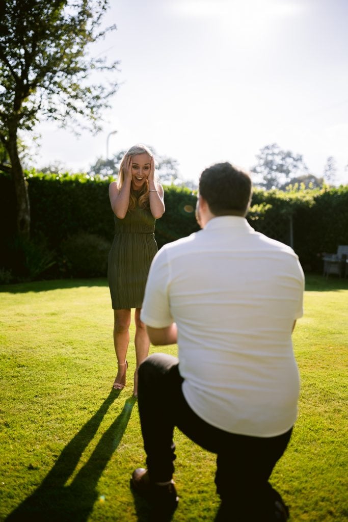 A man is proposing to a woman in the grass.