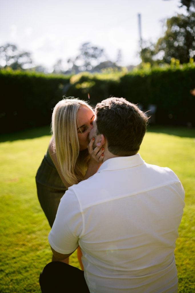 A man kissing a woman in the grass.